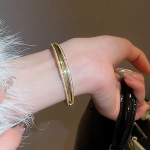 Close-up of 18k gold plated bangle featuring a zircon-encrusted edge and geometric cutout