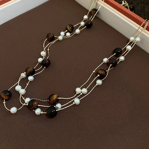 Dettaglio di una collana a strati con perle vintage e perle occhio di tigre in scatola