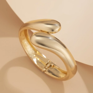 Detailed close-up of a polished gold minimalist open bracelet with water drop shaped ends