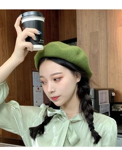 Detail of wool beret in grass green showing soft felt texture on a female model