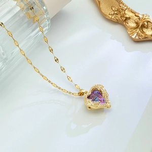 Golden heart necklace with purple gemstone and wings on a vintage decorative display