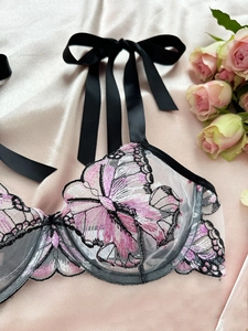 Detail of delicate butterfly embroidery on white mesh bra with black satin shoulder ribbons