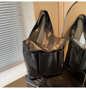 Macro detail of black PU leather tote bag featuring three front utility pockets and soft texture