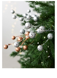 Détail de branches de baies argentées et dorées à paillettes sur un sapin de Noël