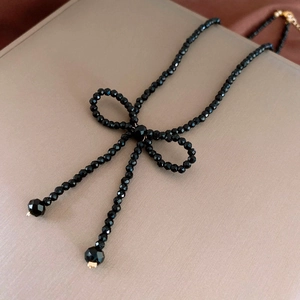Close-up of black faceted beads with a bow design and golden clasp on a jewelry box