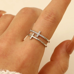 Close-up of double-layer silver cross ring with sparkling zircon stones on model's finger