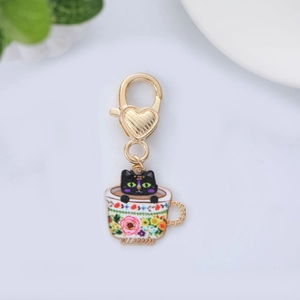 Detail of enamel cat charm in floral teacup with golden heart-shaped lobster clasp