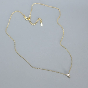 Detail of s925 silver gold-plated necklace with a small pearl and zircon pendant