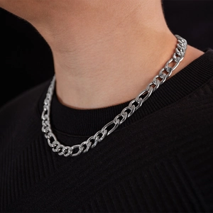 Close-up of polished stainless steel Figaro chain necklace worn on a male model neck