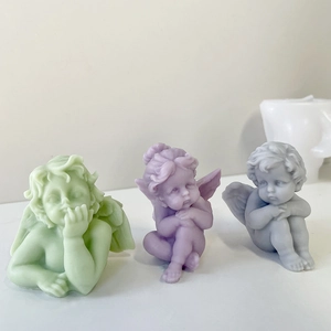 Three cute angel-shaped scented candles in light green, purple, and gray colors