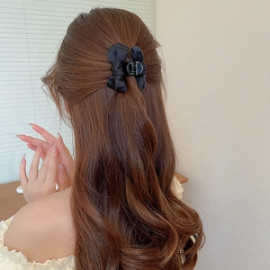 Dettaglio di un elegante fermaglio per capelli a fiocco in raso nero su un'acconciatura
