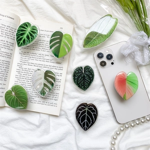 Detailed overhead shot of tropical leaf phone grips with glossy finish on aesthetic background