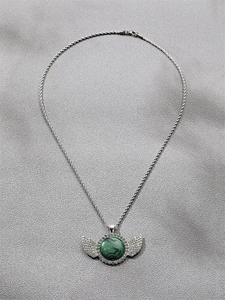 Détail du pendentif aile argenté avec pierre verte et zircons sur chaîne torsadée
