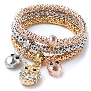 Detailed view of three owl charm popcorn chain bracelets in gold, silver, and rose gold