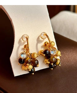 Macro shot of tiger eye stone earrings with zircon and frosted gold beads detail
