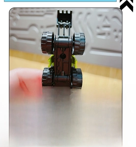 Close-up of mini construction toy keychain base showing durable tires and chassis detail