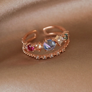 Macro detail of rose gold open ring with colorful zircon stones on champagne silk