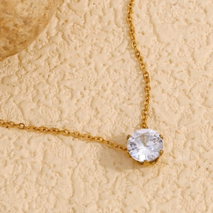 Détail d'une fine chaîne en or avec un pendentif couronne en zircon blanc rond brillant