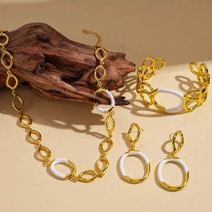 Ensemble bijoux dorés et émail blanc sur support en bois vintage chic