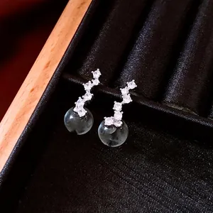 Elegant silver earrings with zircon stones and blue round drop pendant on black velvet