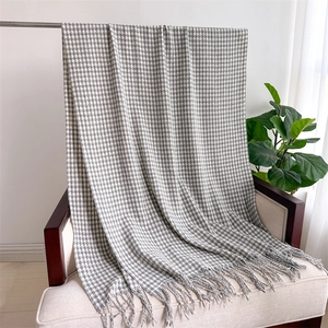 Detailed view of gray houndstooth cashmere scarf with soft fringes on a chair