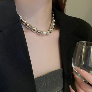 Detail of irregular silver metal beads choker with a central pearl on a model's neck