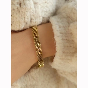 Golden woven mesh chain bracelet in bold metal style shown on a sweater sleeve