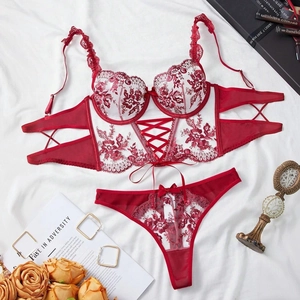 Flat lay of red floral lace lingerie set with corset style bra on white fabric