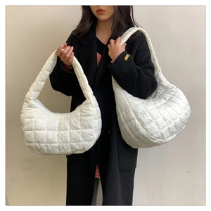 Close-up of white quilted puffer shoulder bag showing texture and stitching details