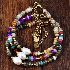 Détail de perles de pierre colorées et perles de culture baroques sur bracelets dorés