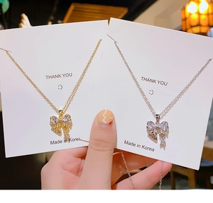 Détail du pendentif nœud serti de zircons sur des colliers en or et en argent
