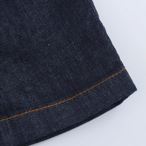 Gros plan détaillé du tissu denim bleu foncé avec surpiqûres orange sur la robe