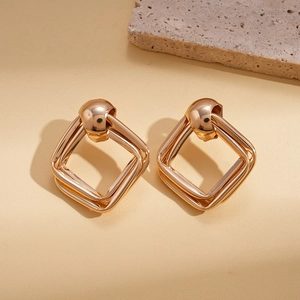 Gros plan de boucles d'oreilles carrées dorées géométriques avec une finition brillante