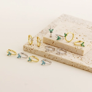 Detailed shot of emerald and crystal butterfly earrings on stone display stands