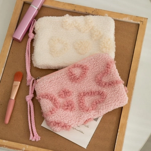 Detail of plush lamb wool makeup bag with heart texture and portable lanyard strap