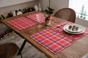 Set of 4 festive red plaid Christmas placemats on a rustic wooden dining table