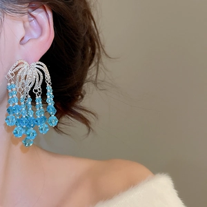 Macro shot of long tassel earrings featuring light blue faceted crystal beads and silver chains