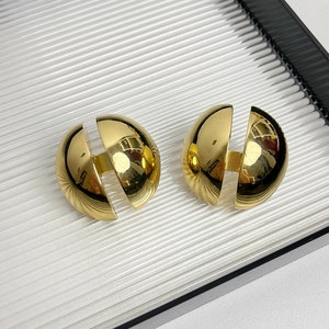 Vue macro de boucles d'oreilles demi-sphériques dorées avec finition métallique polie