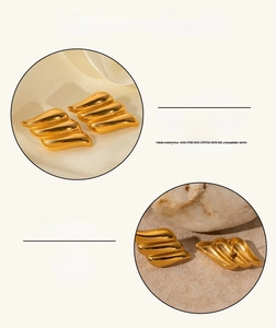 Detail of 18k gold plated wave-shaped stainless steel earrings on marble surface