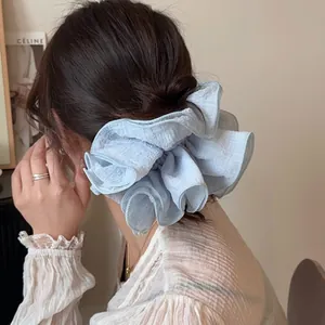 Elegant light blue tiered ruffle hair scrunchie with soft textured fabric on model