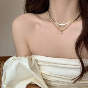 Detail of double-layer gold snake chain necklace with a single zircon pendant on model