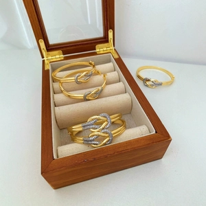 Luxuriöses vergoldetes Knotenarmband mit Kristallen in einer hölzernen Schmuckschatulle