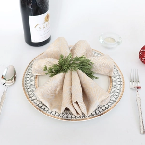 Detail of a champagne gold wavy table setting with pine needles and festive decor