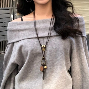 Modèle portant un long collier vintage avec des pendentifs plume de bronze, étoile et perle