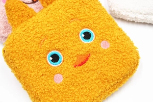 Nahaufnahme der gelben Plüschtasche mit süßem Sticktiergesicht und weicher Materialstruktur