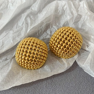 Detailansicht der goldenen Ohrstecker mit einer hohlen, gewebten Kugelperlenstruktur