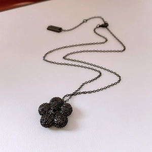 Detailed close-up of a sparkling black floral pendant with textured micro-inlaid stones