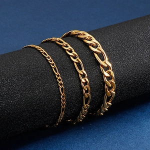 Three gold stainless steel Figaro chains in various widths draped on a black cylinder