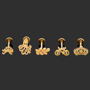 Lot détaillé de cinq clous en acier doré incluant motifs feuille, couronne et bicyclette