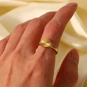 Gros plan d'une bague soleil empilable plaquée or 18 carats sur fond de soie